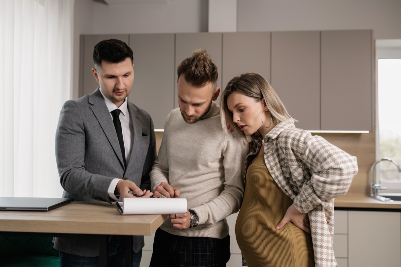 A couple reviews and signs documents with an agent, navigating the paperwork of a major decision